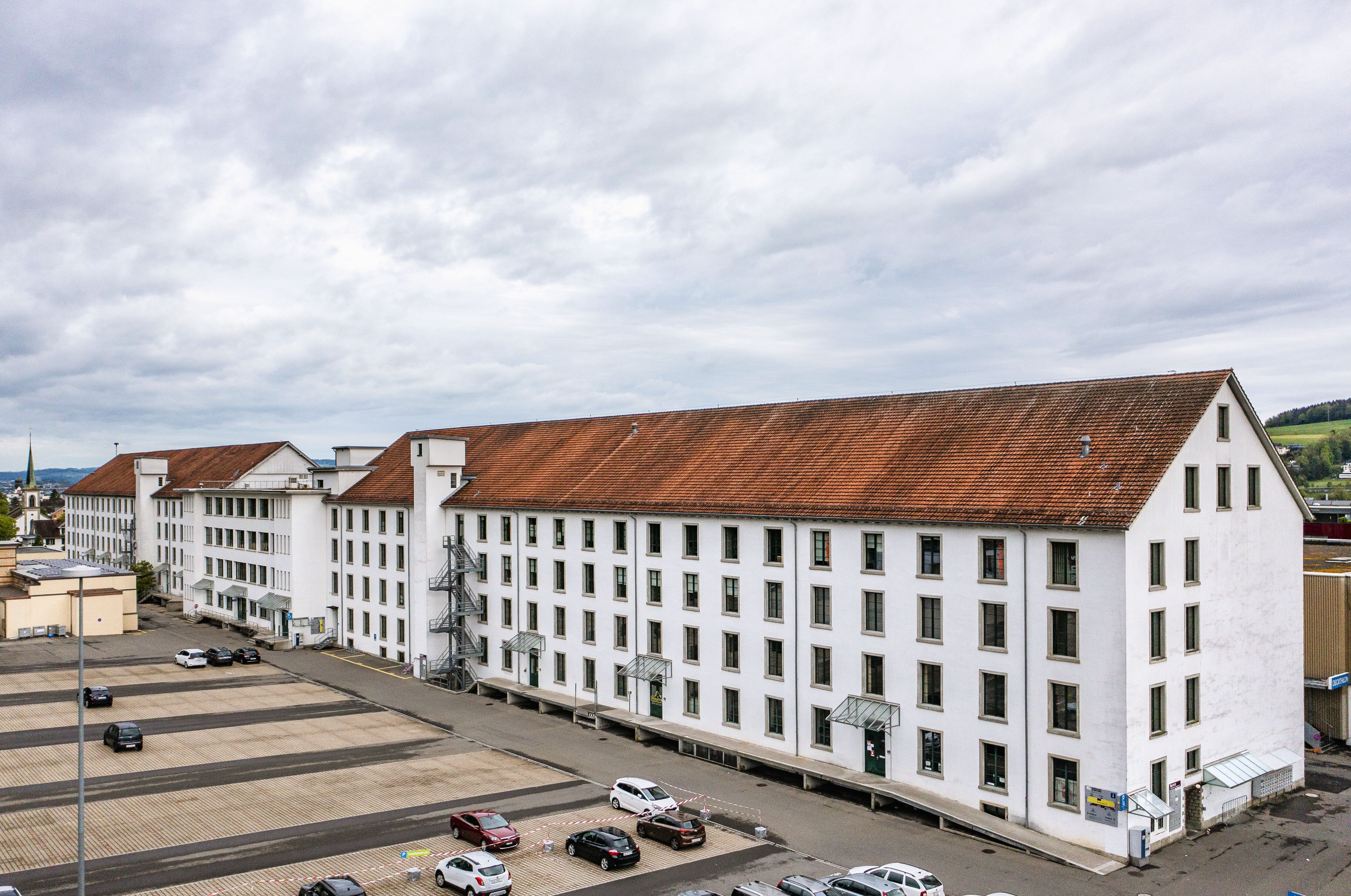 Spinnereigebäude an der Lorze bestehend aus dem Mittelbau von 1947 und zwei seitlichen Fabrikflügeln von 1853/54 und 1857/58.