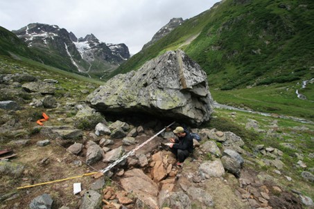 Image d'un rocher tombé, examiné par un archéologue.